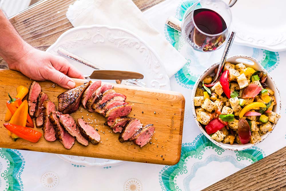 Platter of sliced flank steak with glass of wine